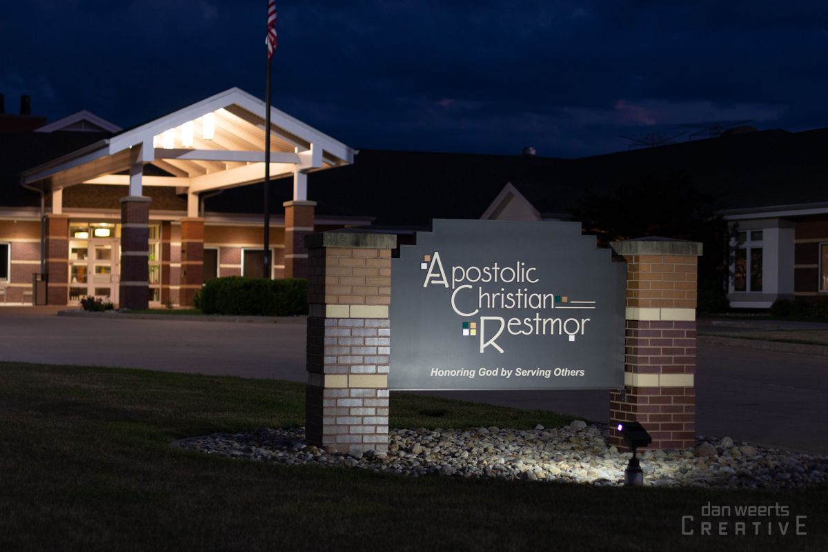 A sign for Apostolic Christian Restmor is lit up at night