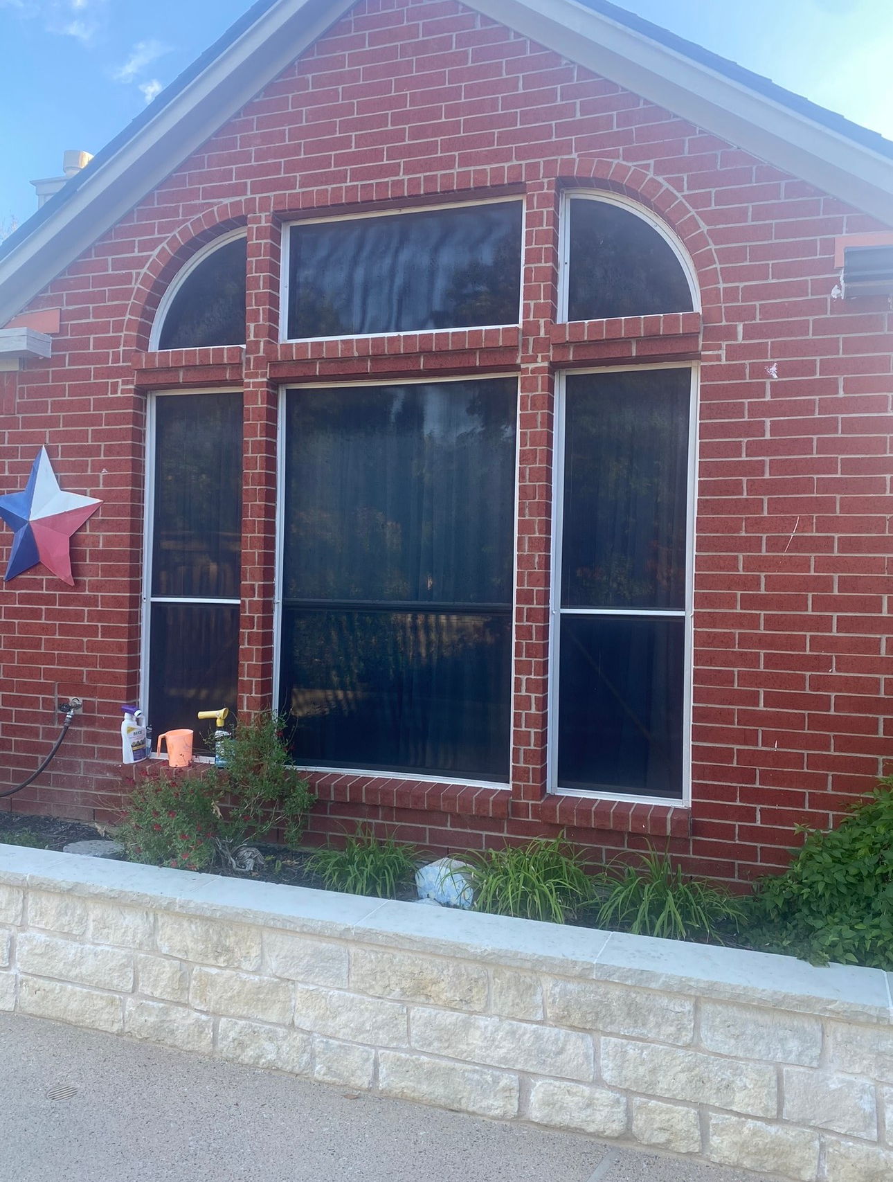 A red brick house with screened in windows and a texas flag