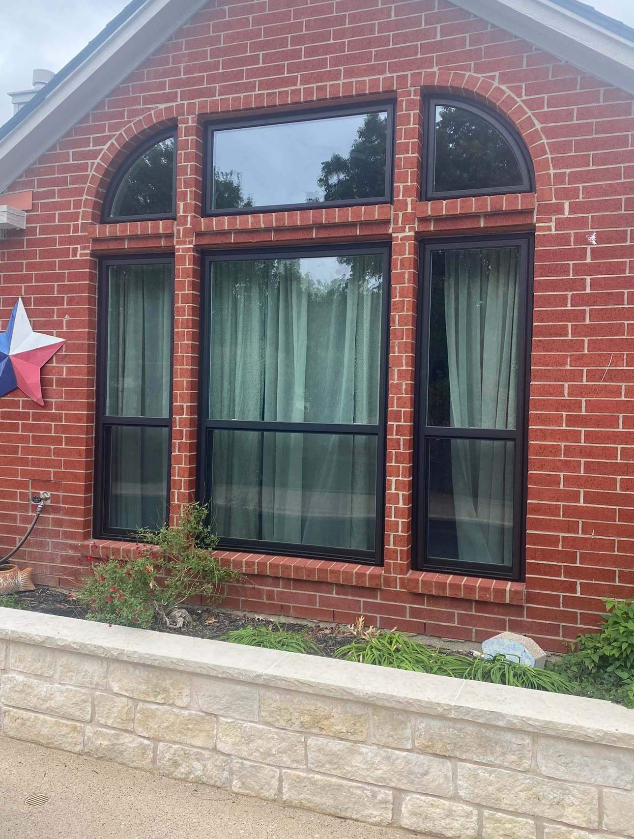 A red brick house with black windows and curtains