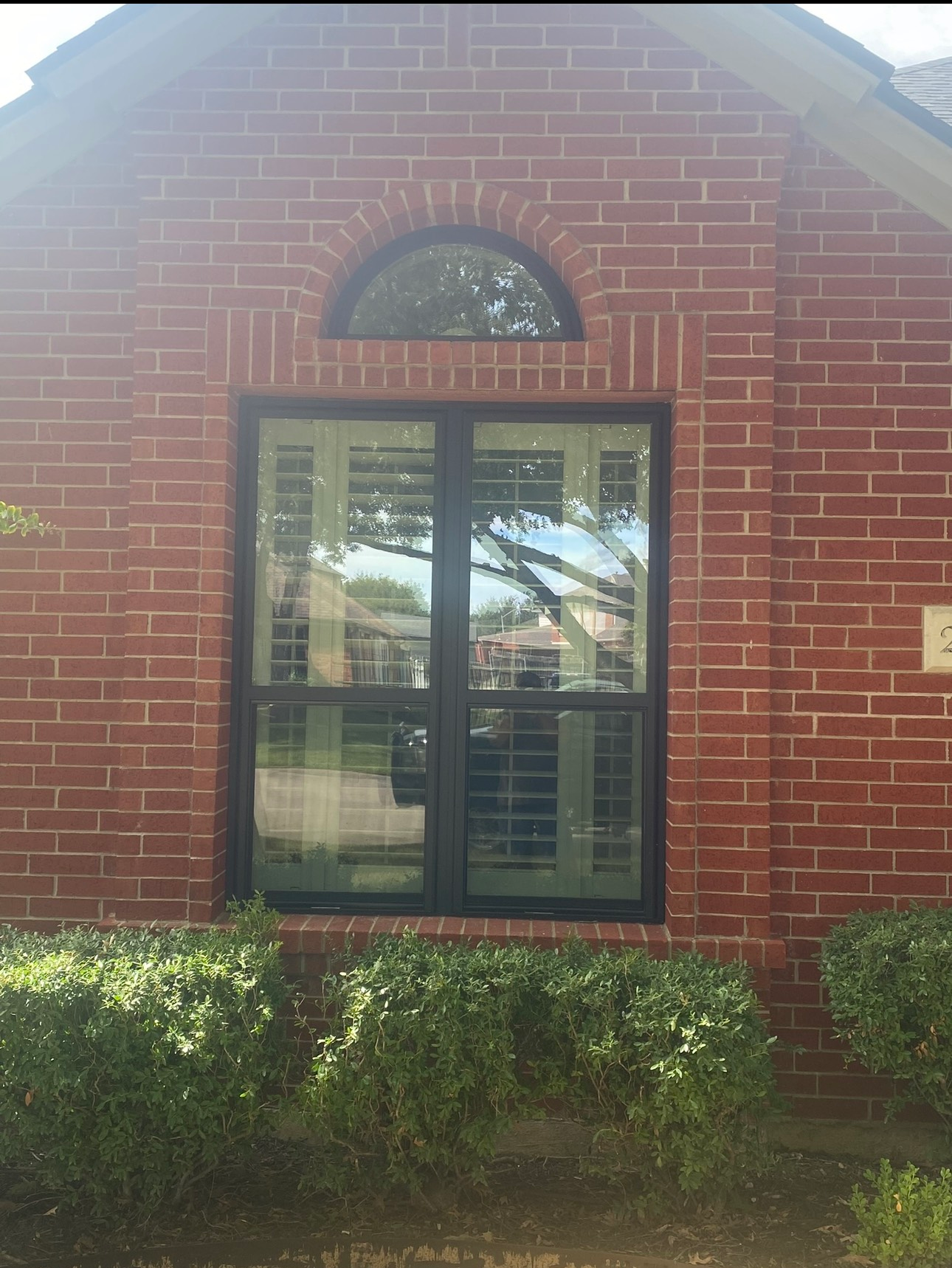 A brick building with a large window and shutters