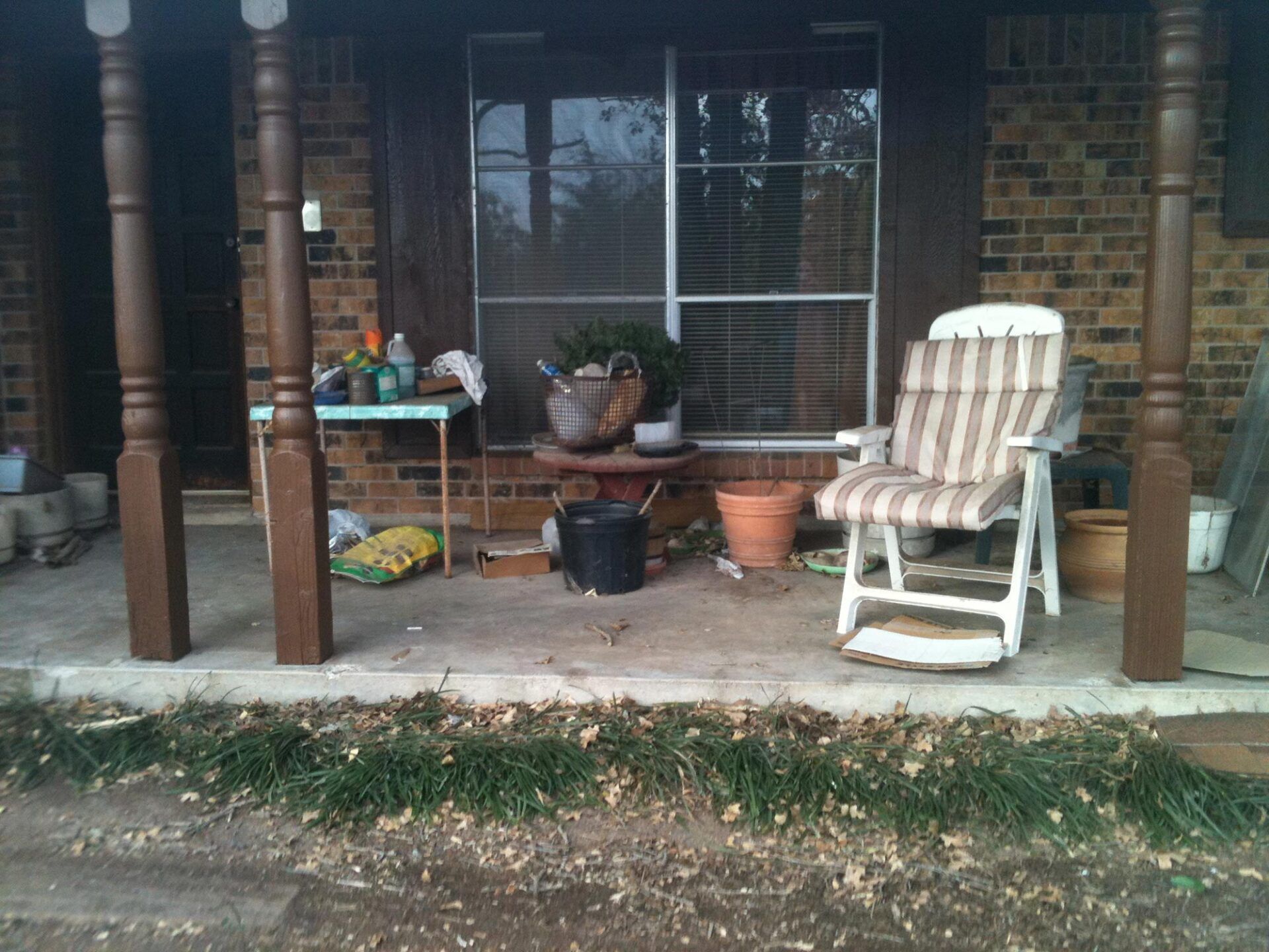 A porch with a rocking chair and potted plants