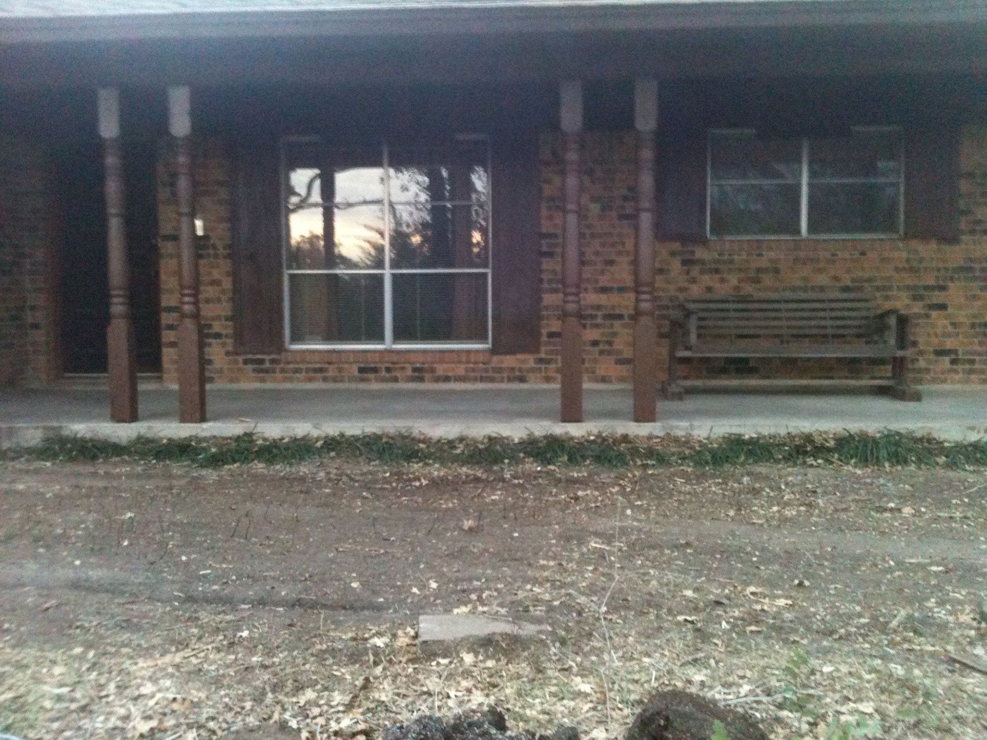 A brick house with a porch and a bench