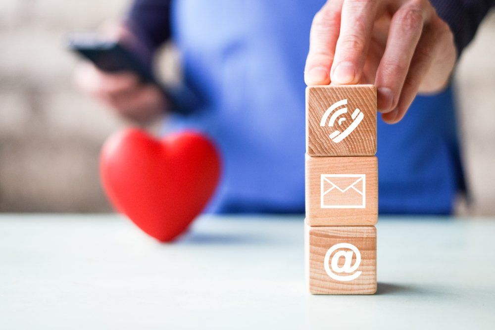 A person is stacking wooden blocks with contact icons on them.