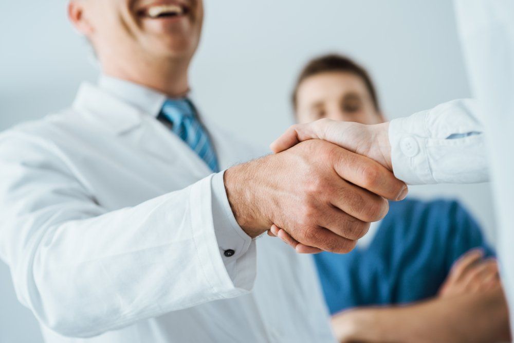 A doctor is shaking hands with a patient in a hospital.