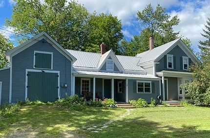 A blue house with a white roof and a green garage next to it.