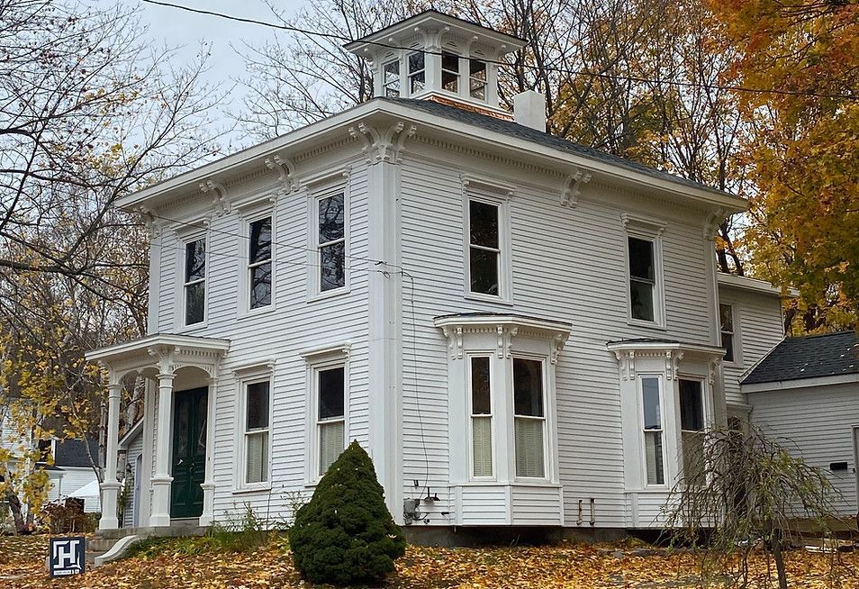 A large white house with a roof that has a dome on top of it
