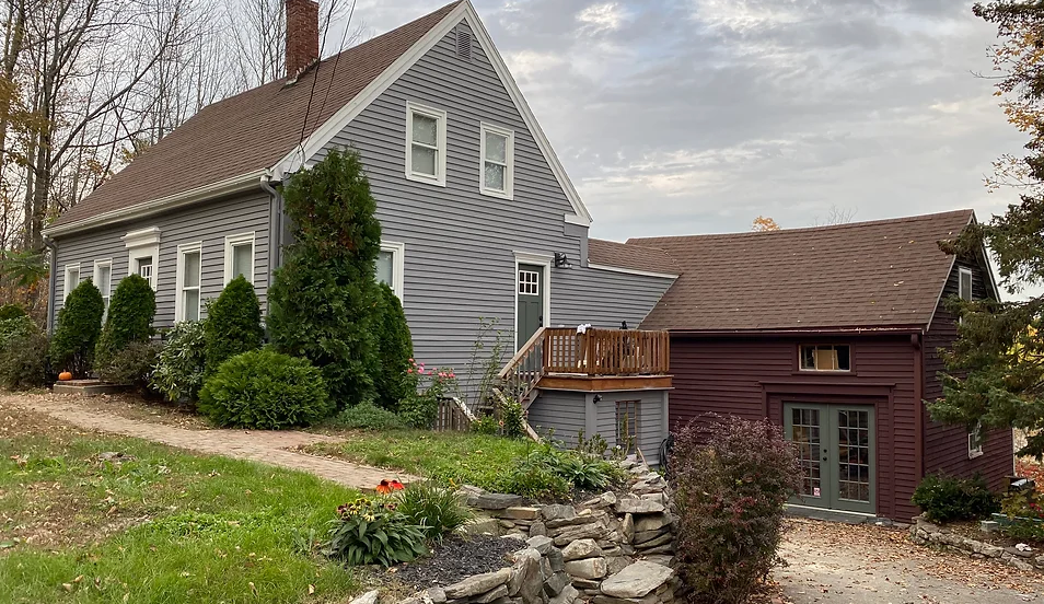 A large gray house with a red garage next to it.