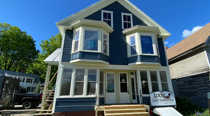 A large blue house with a lot of windows is being remodeled.