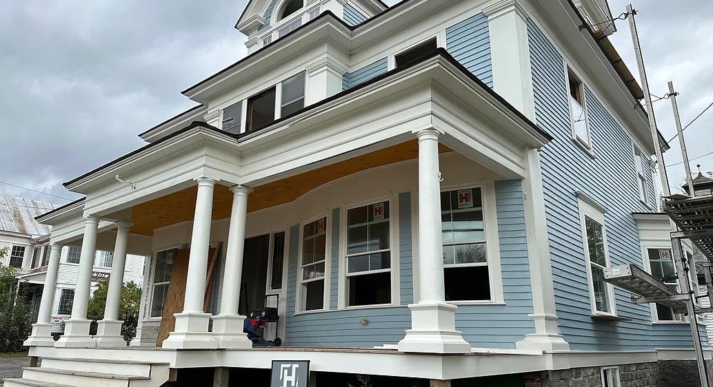 A large blue and white house with a porch and columns.