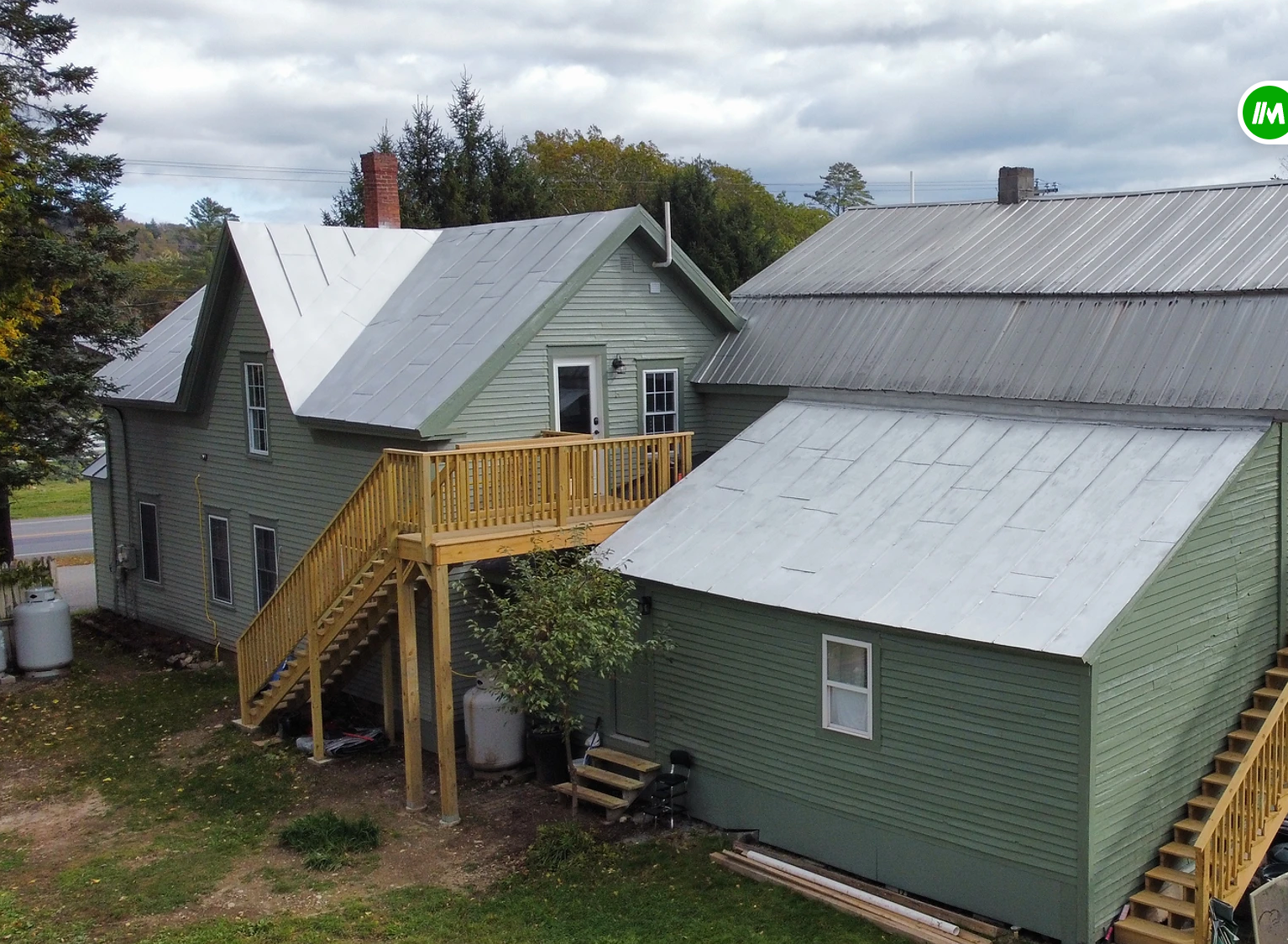 A green house with a metal roof and a wooden deck