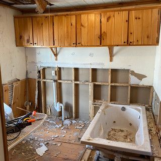 A bathroom is being remodeled with a jacuzzi tub and wooden cabinets.