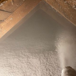 A person is spraying insulation in an attic.