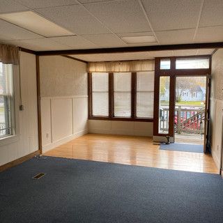 An empty living room with hardwood floors and a large window.