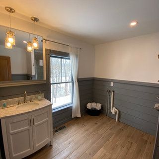 A bathroom with a sink , mirror and window.