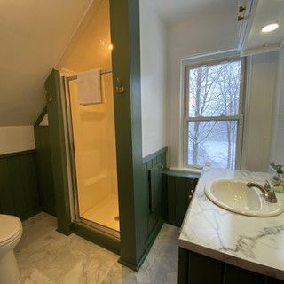 A bathroom with a toilet , sink , shower and window.