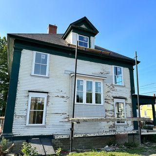 A white house with a green trim is being painted.