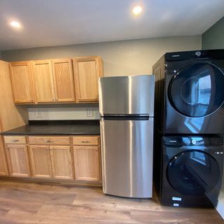 A kitchen with a refrigerator , washer and dryer stacked on top of each other.