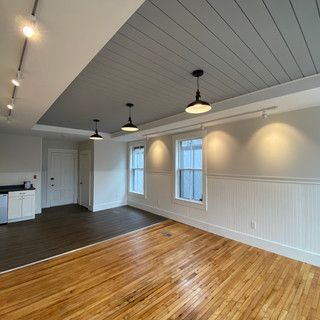 An empty room with hardwood floors and a gray ceiling.