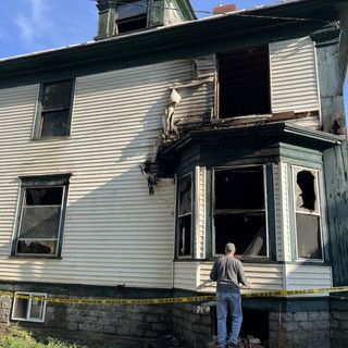 A man standing in front of a house with a broken window