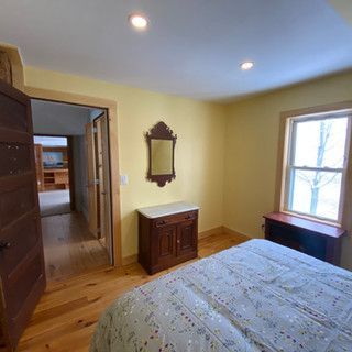 A bedroom with a bed , dresser , mirror and window.