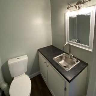 A bathroom with a toilet , sink and mirror.