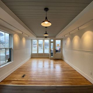 An empty room with hardwood floors , white walls , and a door.