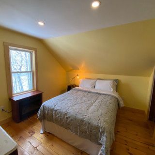 A bedroom with a bed , nightstand , and window.
