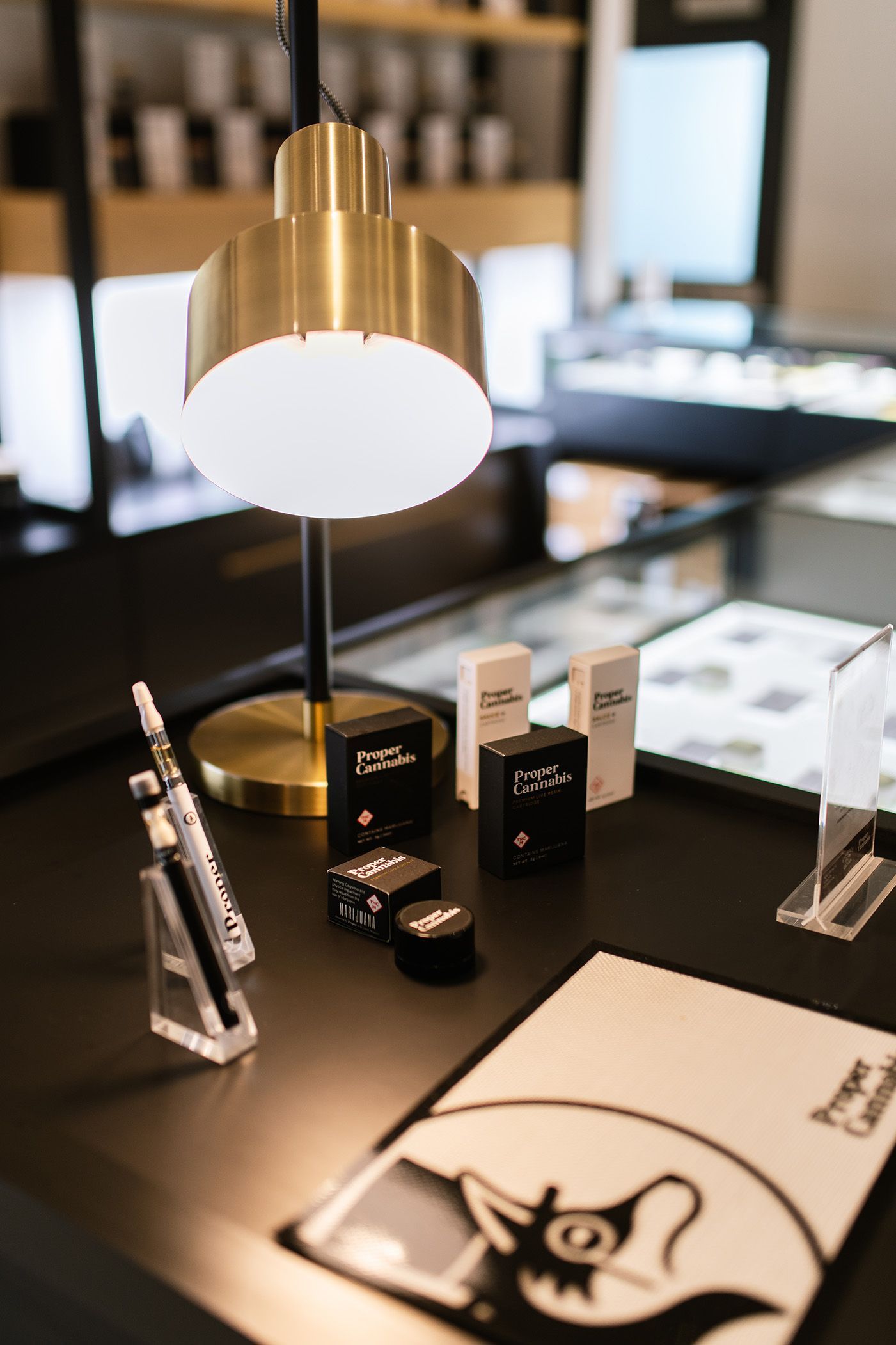 Tabletop display of black cosmetic items and brochures under a brass lamp in a modern office.