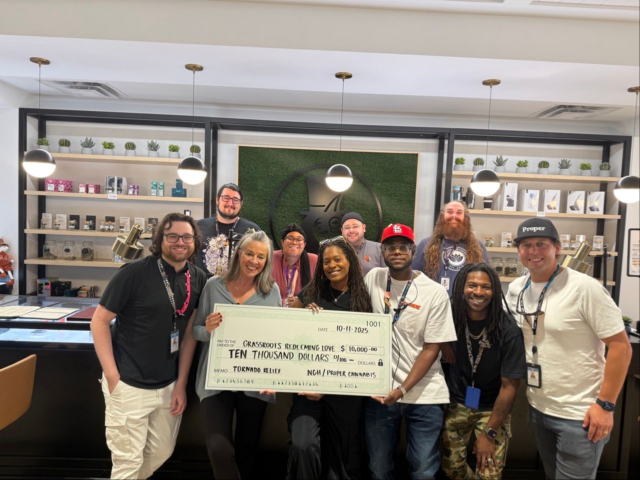 Group of people posing indoors at a restaurant, holding a large check and smiling at the camera.