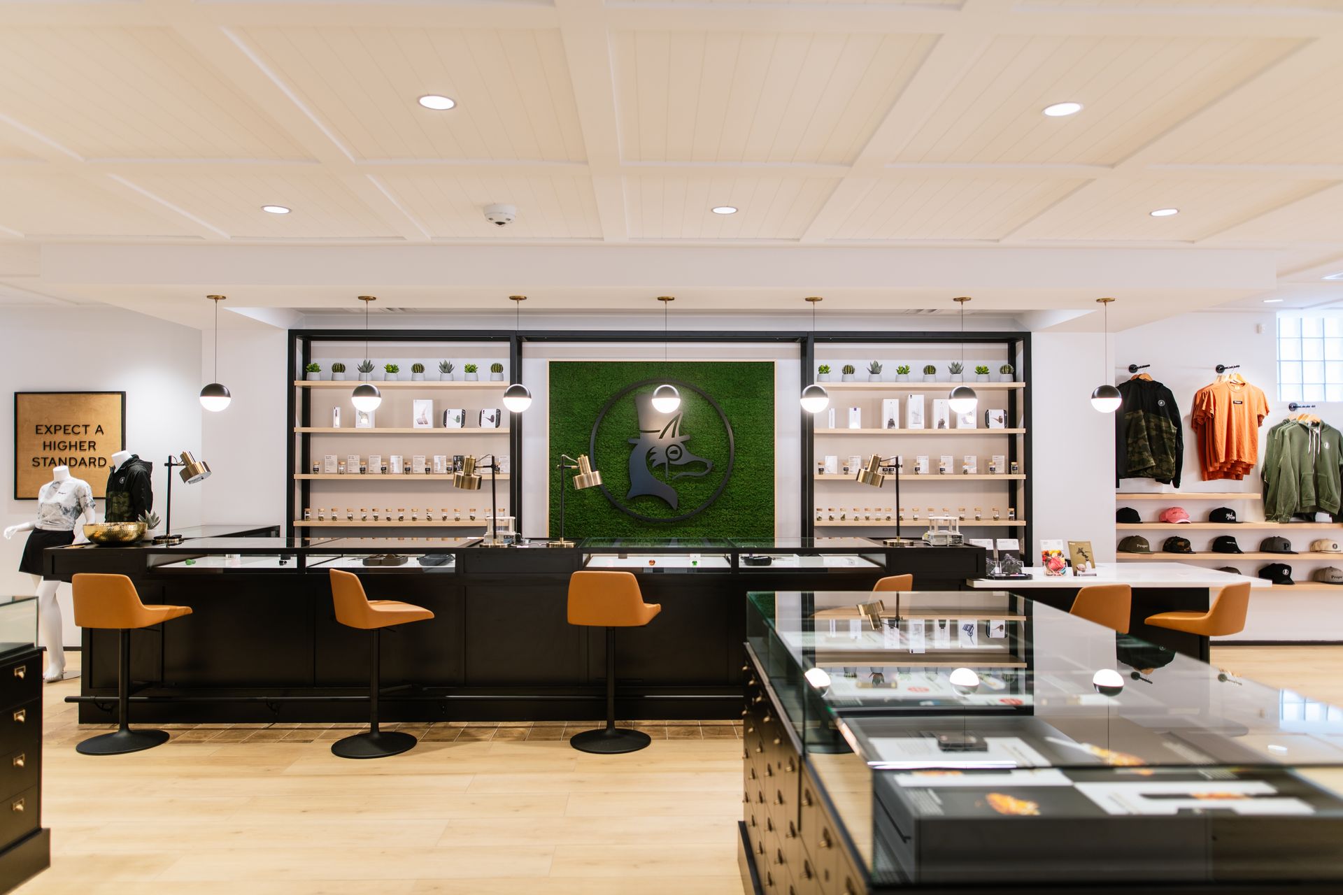 Modern clothing boutique interior with black display counters, shelves, and orange stools under warm lighting