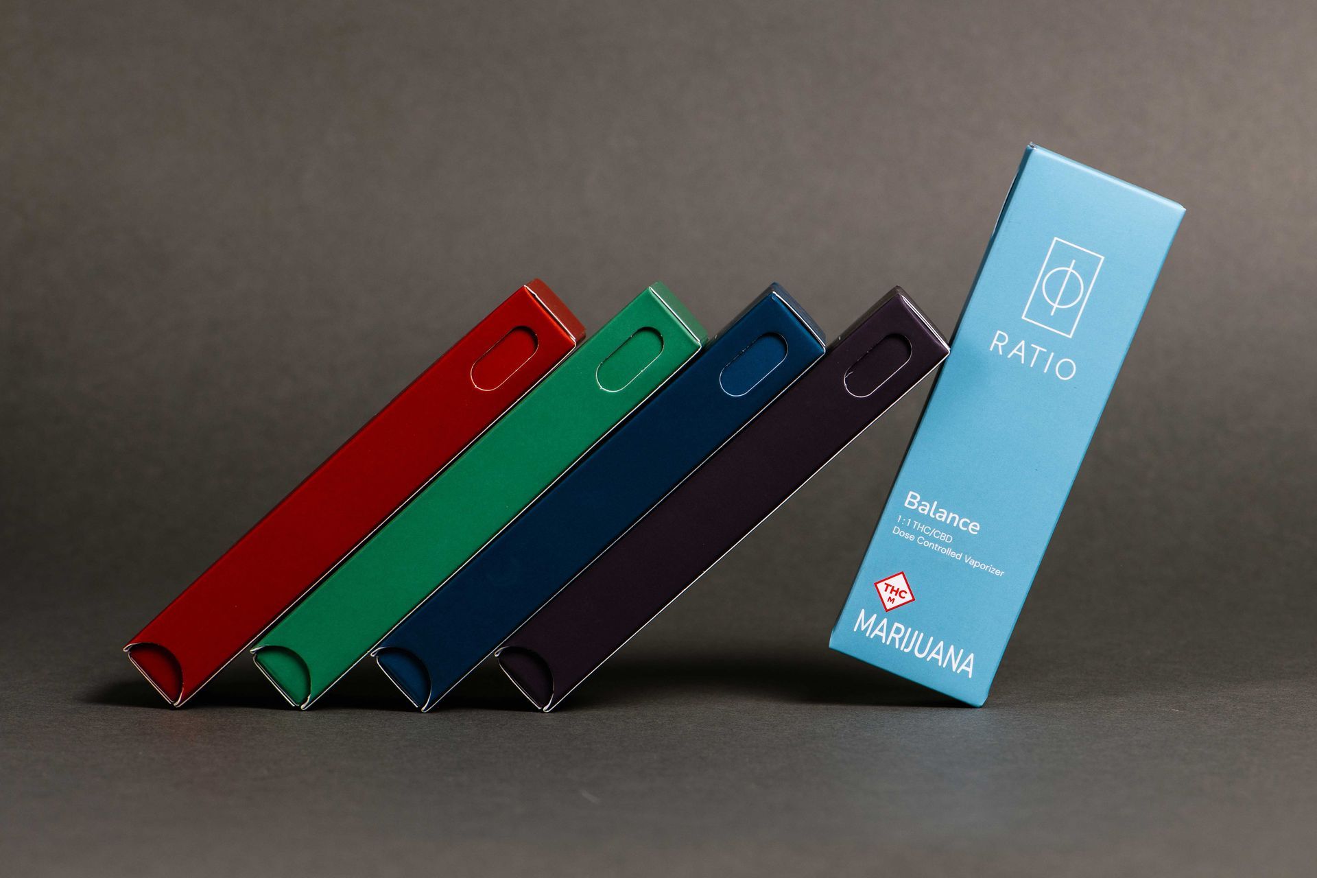 Five colorful folded notebooks or boxes arranged diagonally on a gray surface, with a blue one standing upright.