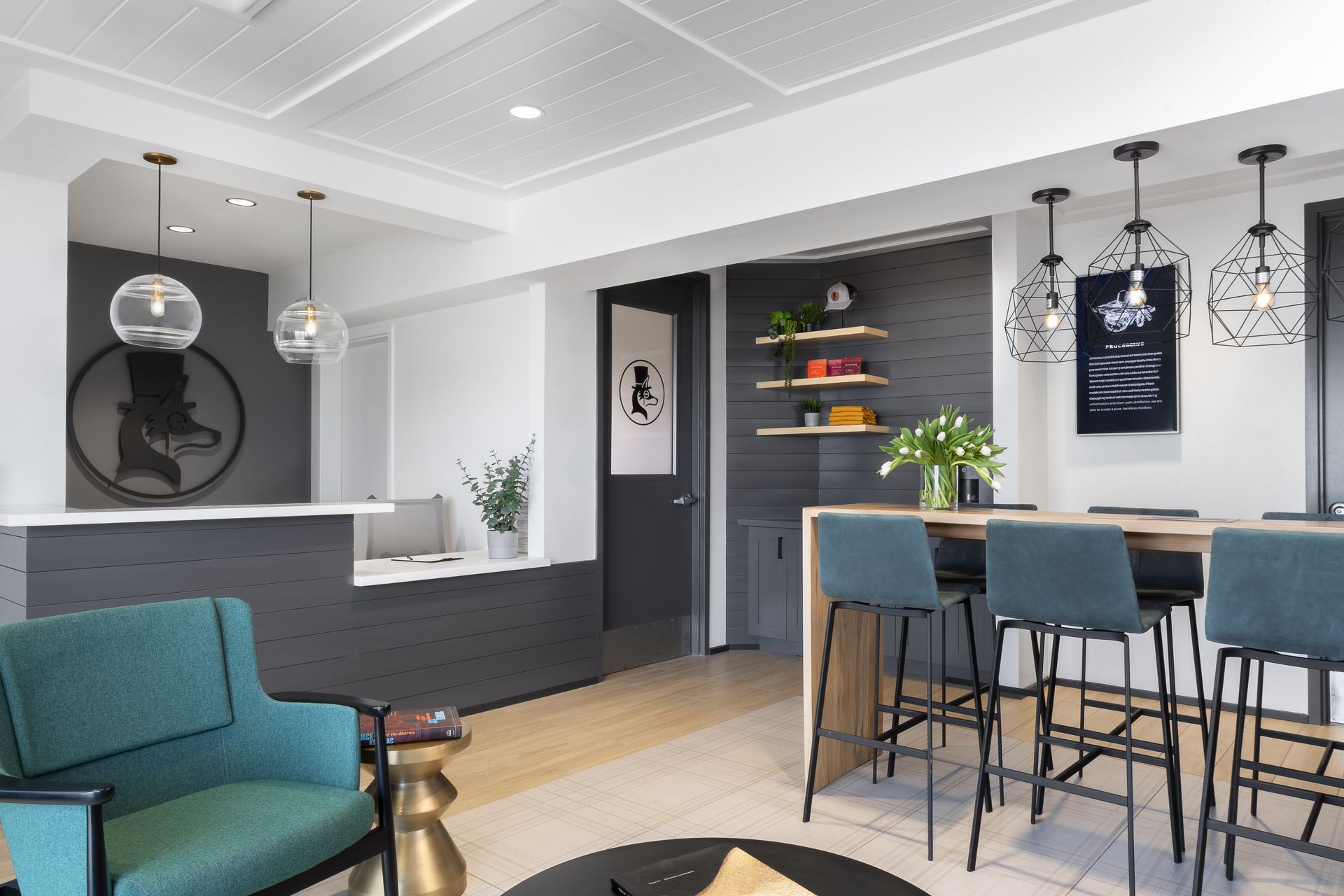 Modern lounge with teal chairs, bar stools, pendant lights, and dark gray accents