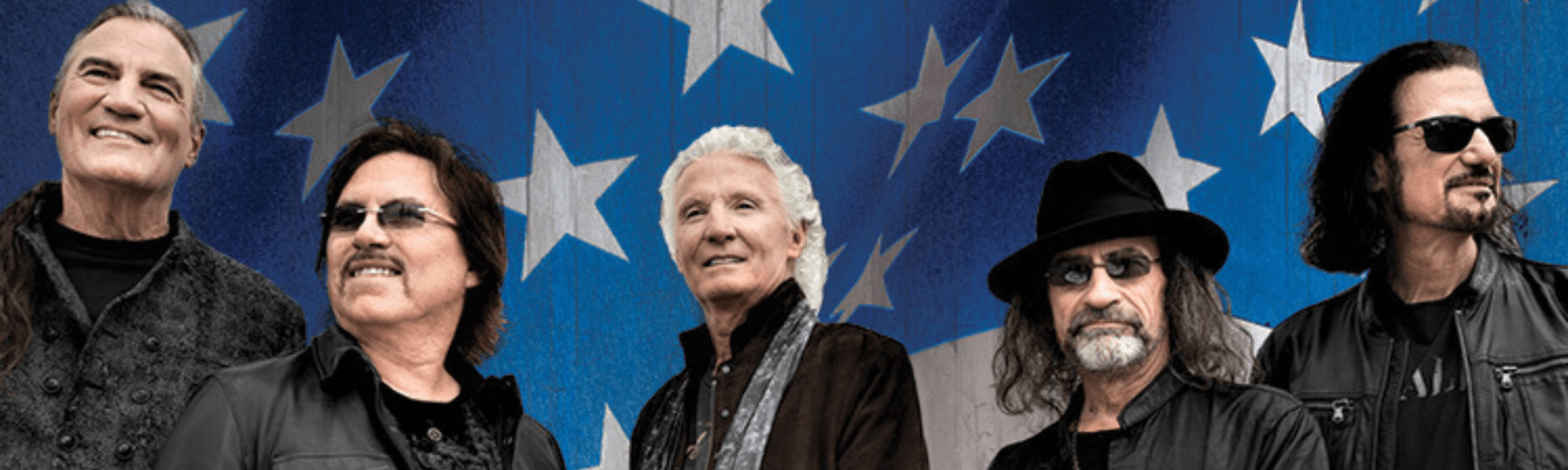 Five men in dark clothing pose before a blue star-patterned backdrop.