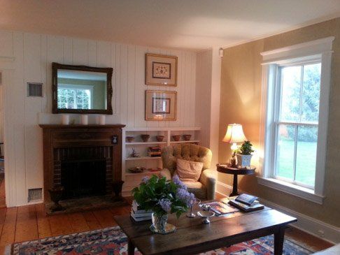 A living room with a fireplace, white paneling, and a coffee table.