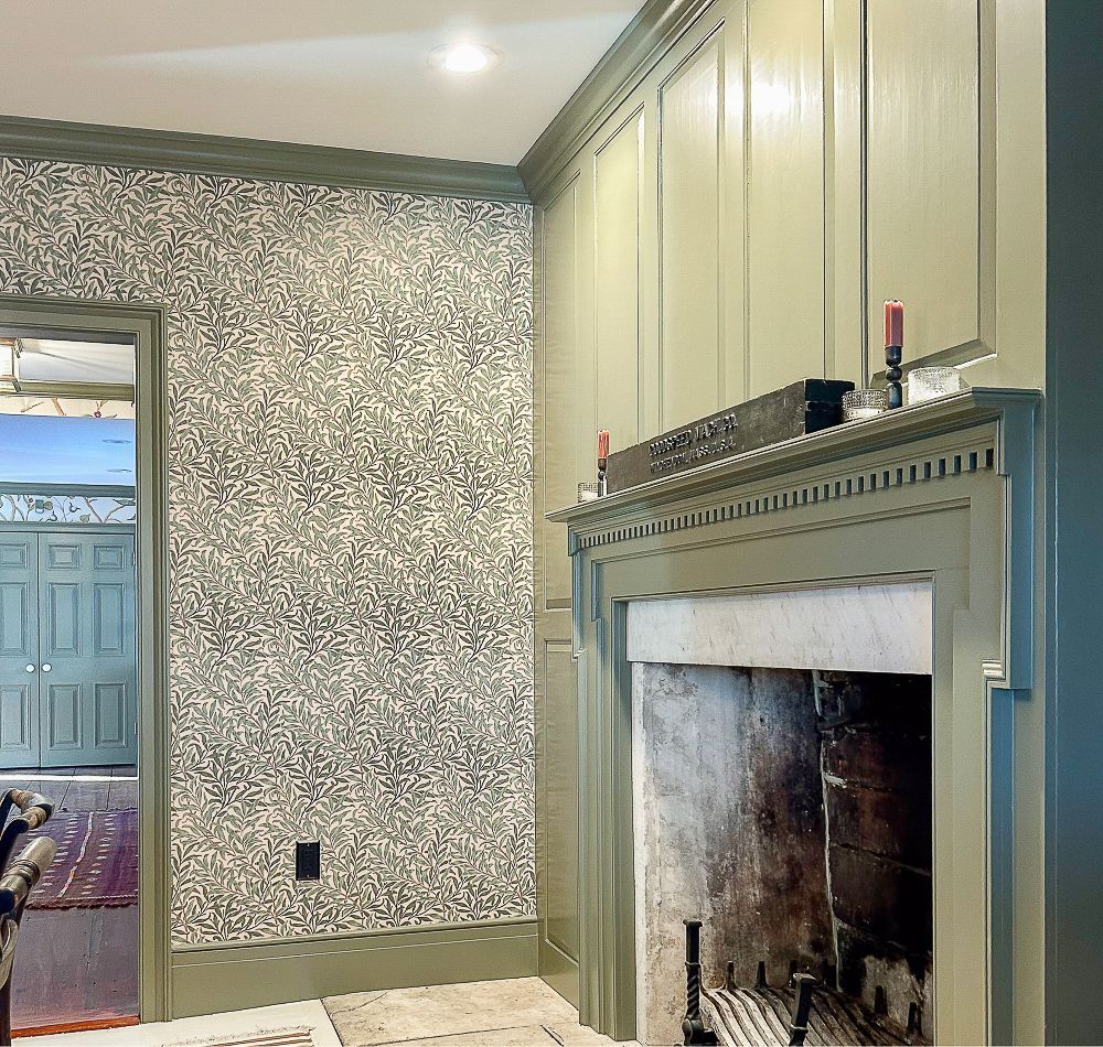 A dining room with a fireplace and green wallpaper