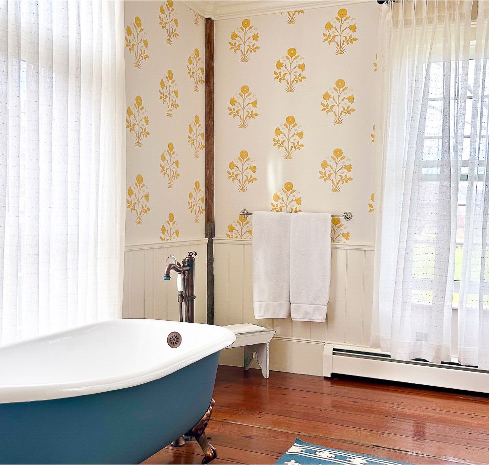 A blue bathtub in a bathroom with yellow flower wallpaper