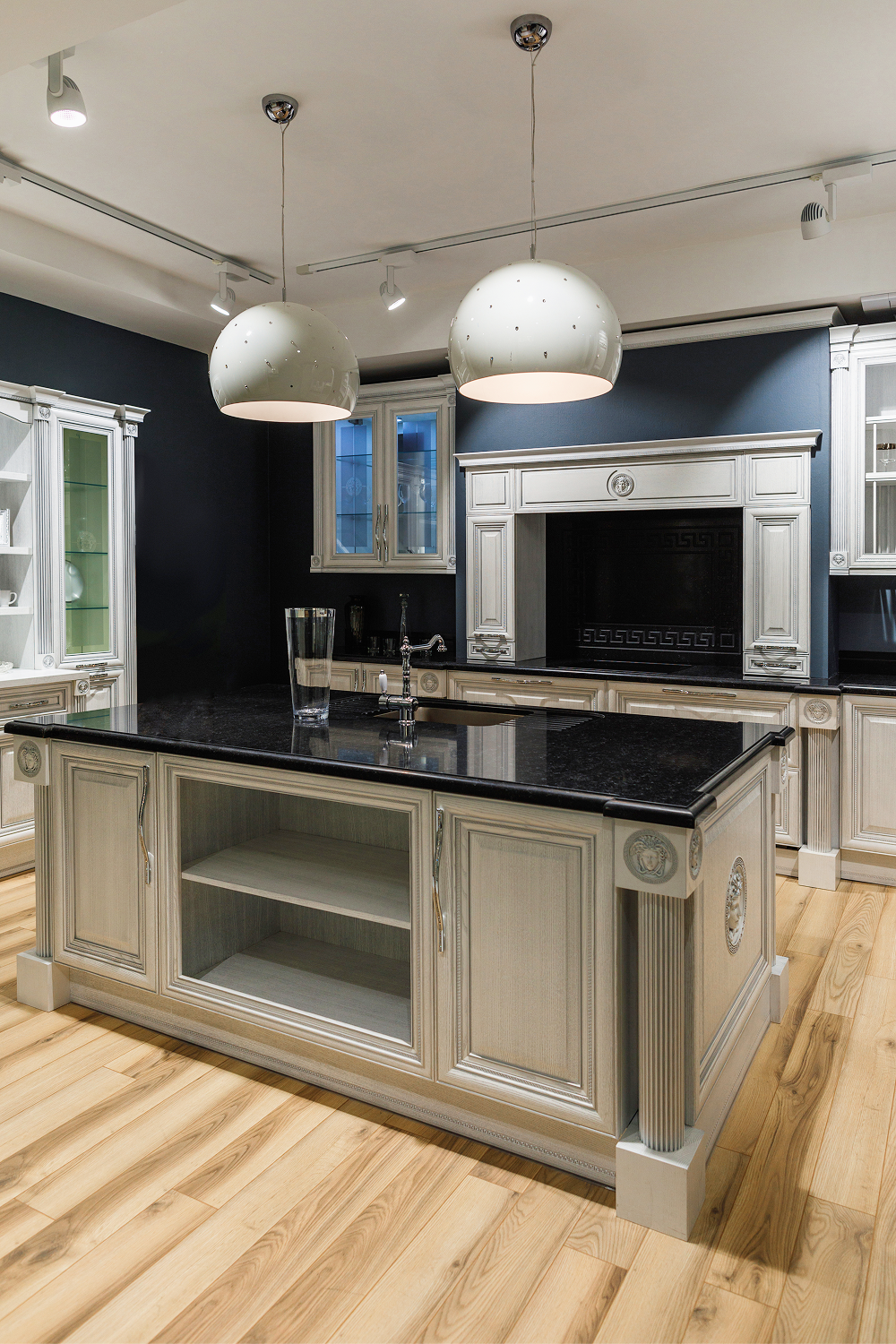 Elegant white kitchen with a dark countertop island and pendant lights.