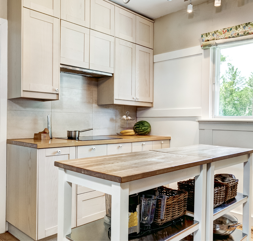 Kitchen with light wood cabinets, countertop and island; window with floral valance.
