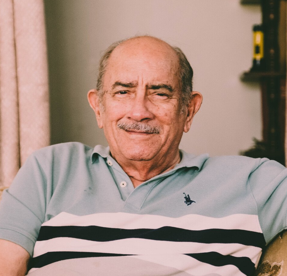 A bald man with a mustache is wearing a polo shirt.
