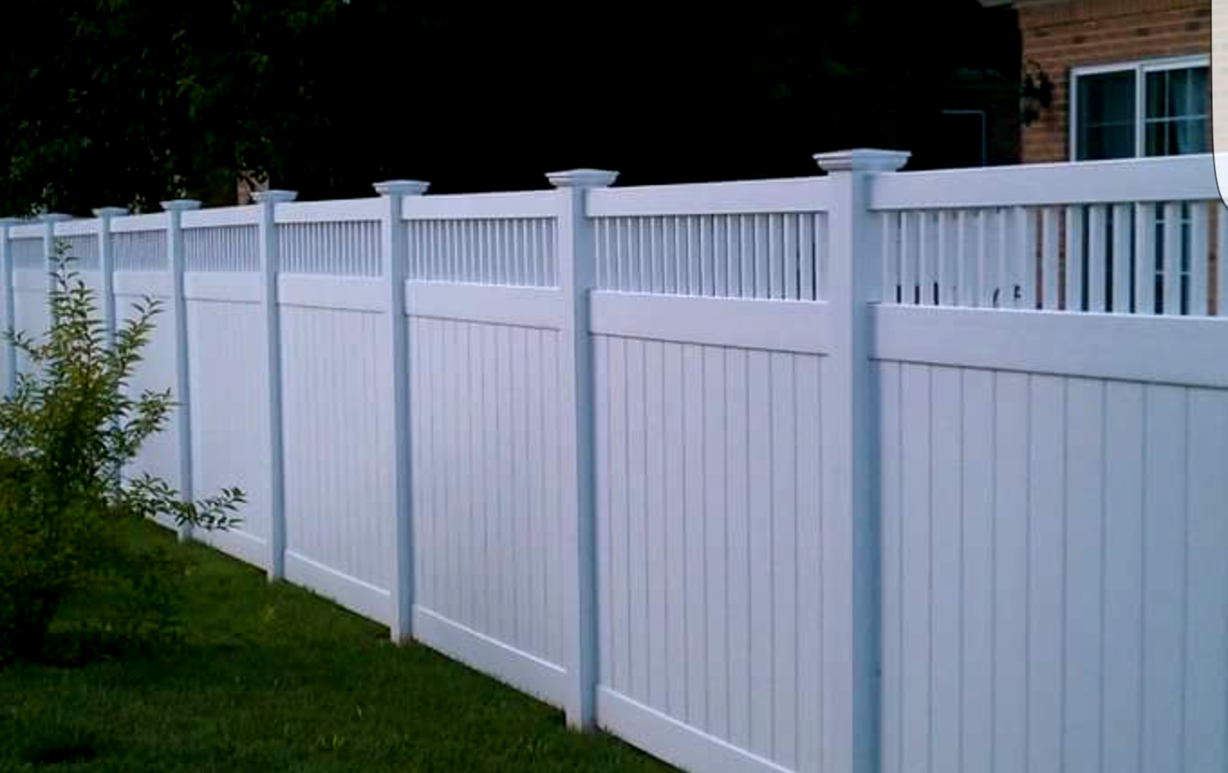 White vinyl fence in front of a grassy lawn, with a house visible in the background.