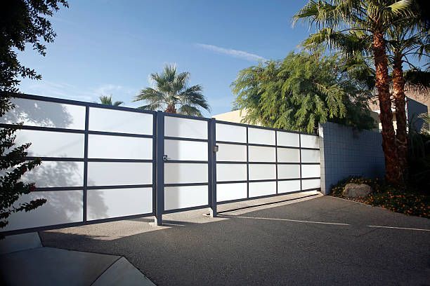 A white fence with palm trees in the background