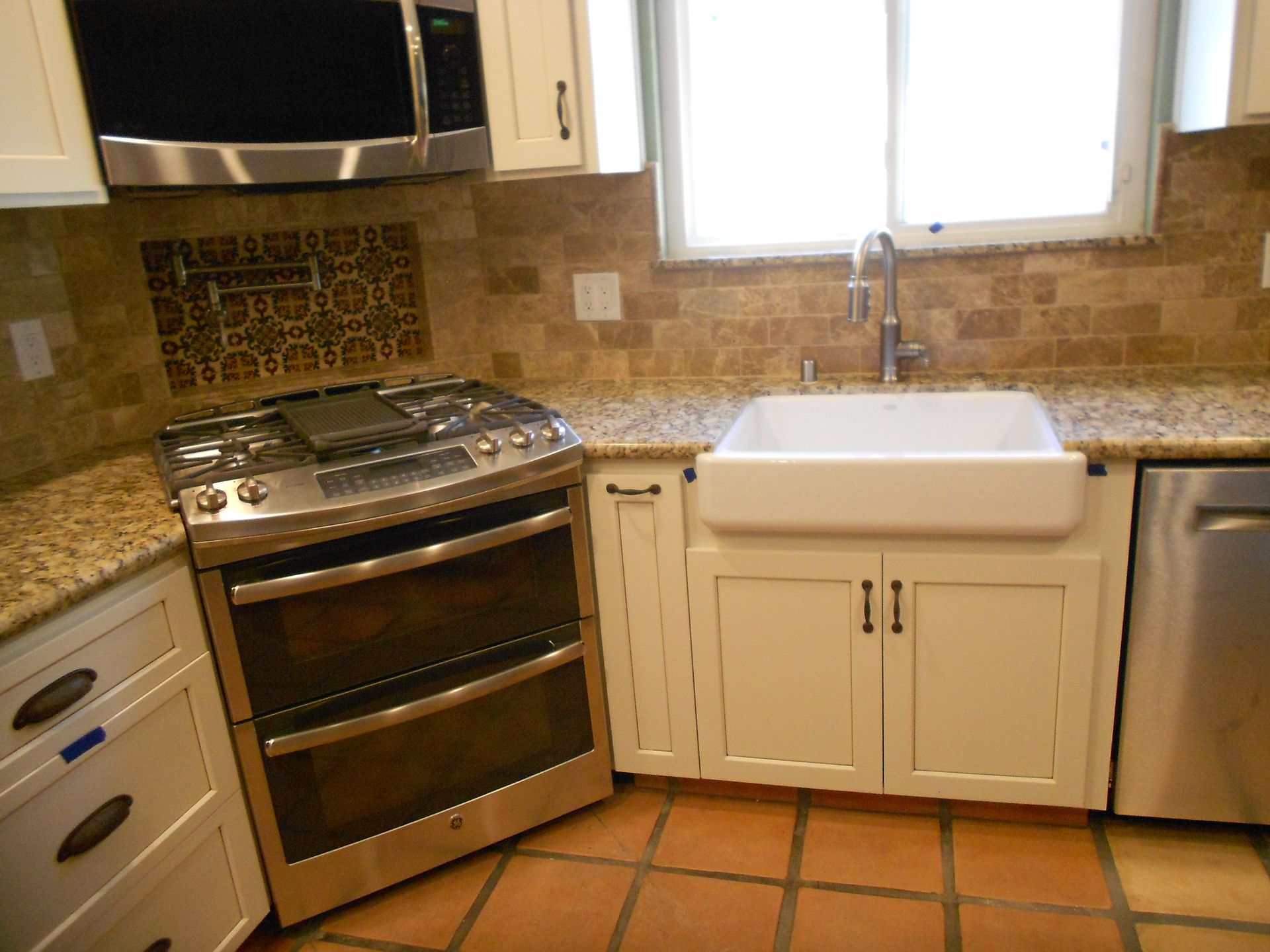 A kitchen with a stove a sink and a microwave