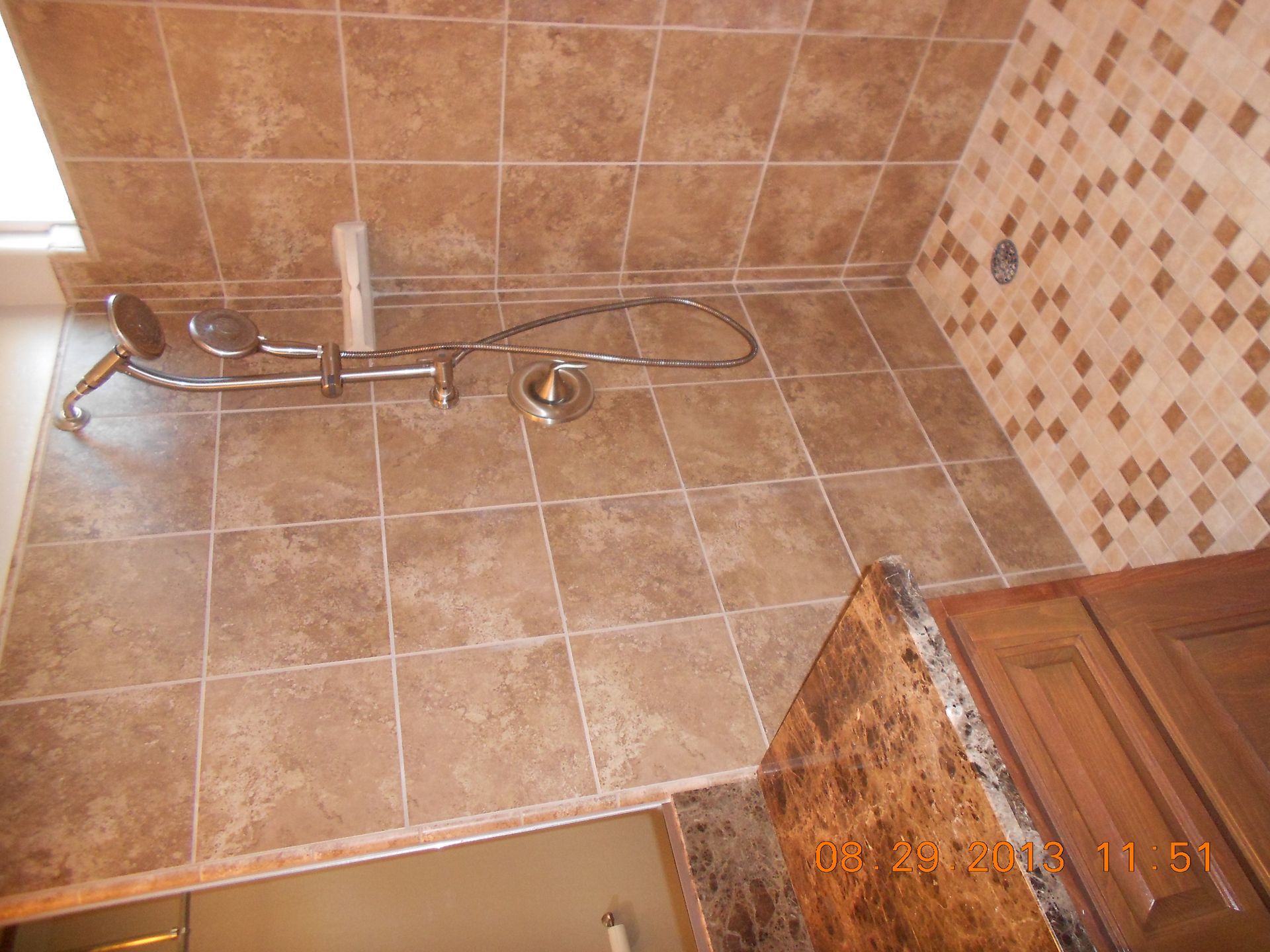 A bathroom with brown tiles and a shower head
