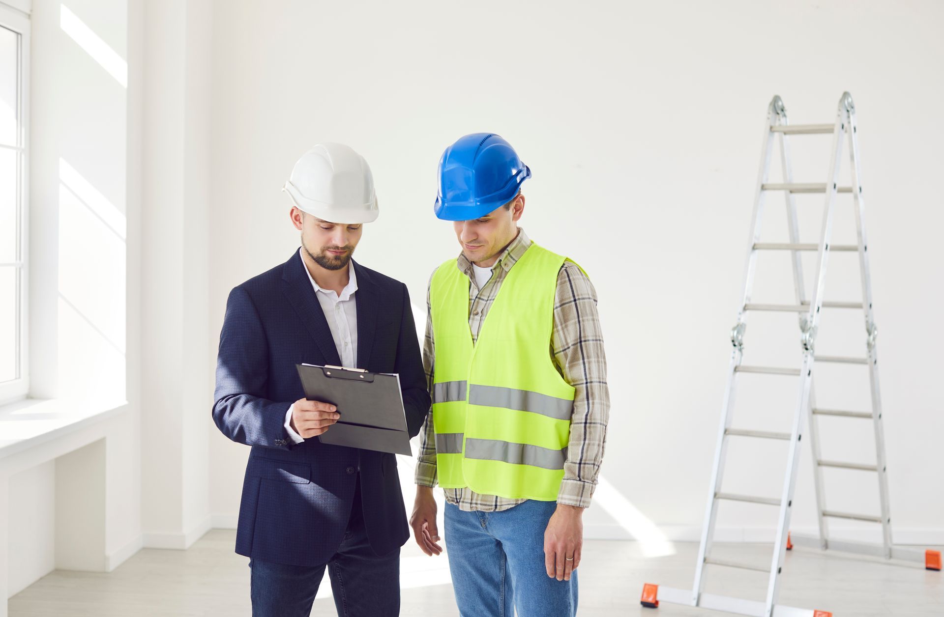 Two men are standing next to each other in an empty room looking at a clipboard.