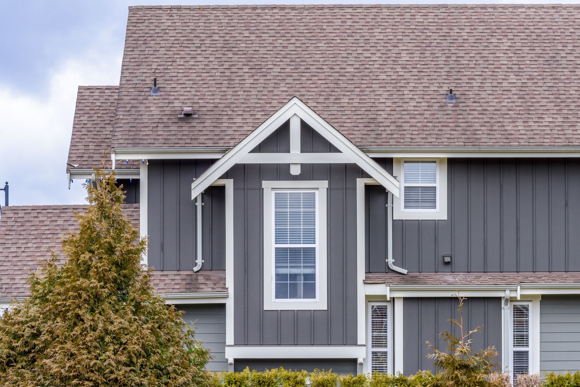 A gray house with a brown roof and a white trim.