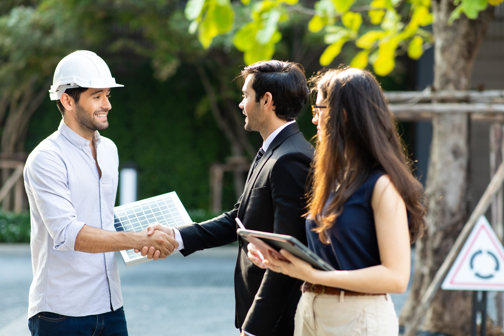 A man and a woman are shaking hands with a construction worker.