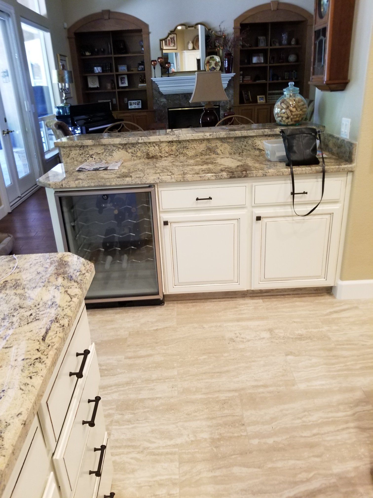 A kitchen with granite counter tops , white cabinets , and a refrigerator.
