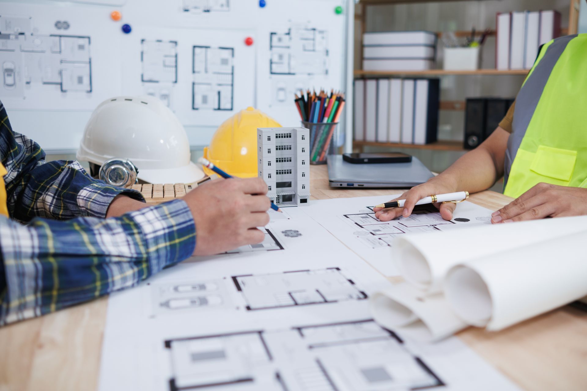 A group of construction workers are sitting at a table looking at blueprints.