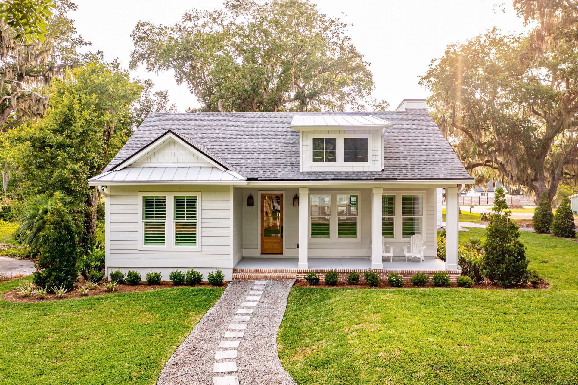 A small white house with a porch and a walkway leading to it.
