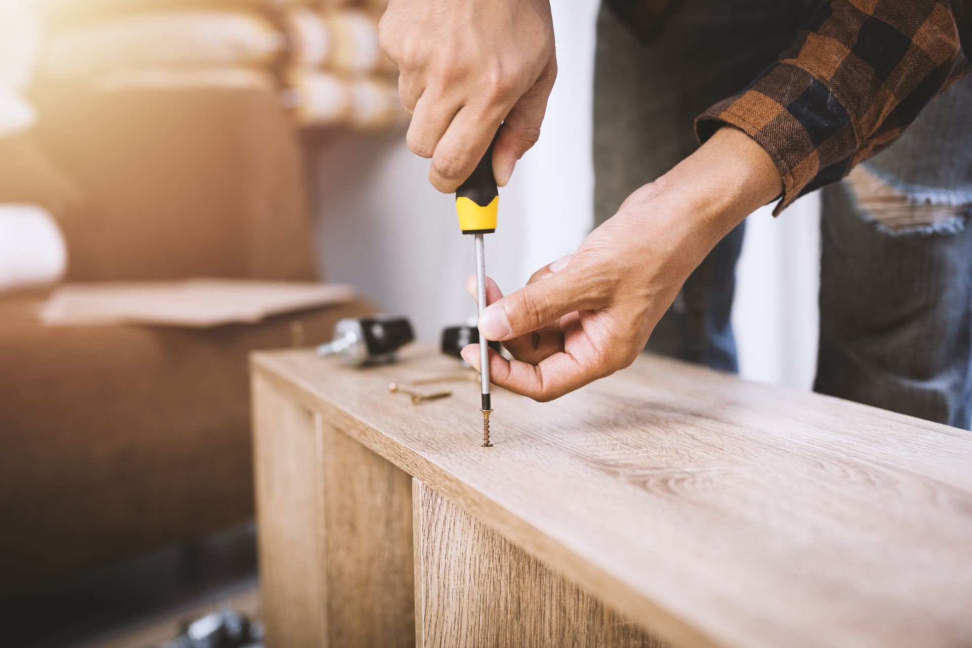 Une personne utilise un tournevis pour assembler une armoire en bois.